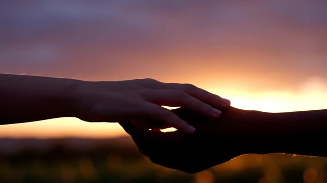 Two people reaching towards each other against a vibrant sunset background