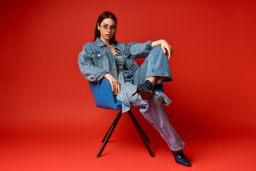 Obraz premium Stylish young woman poses confidently in denim outfit against vibrant backdrop