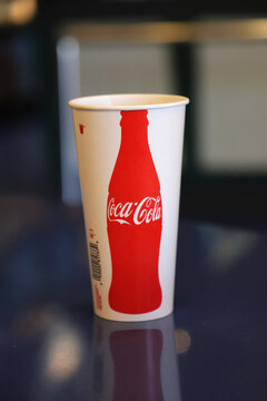 Coca Cola  paper cup on table with copy space and blurred background. Cocke classic