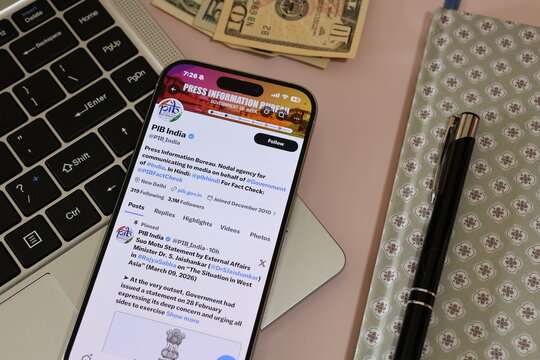 Kiel, Germany - 03-10-2026: X (Twitter) Profile of Indian government media bureau PIB India displayed on smartphone lying on a laptop keyboard