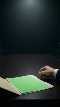 Hand Opening Confidential Folder Revealing Green Screen for Business Presentation or Secret Information