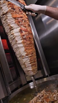 Chef Cutting Chicken Shawarma from Rotisserie Skewer in Restaurant Kitchen