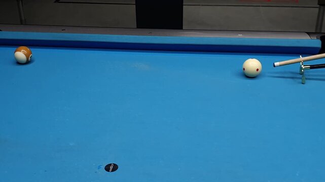 Cue stick and billiard ball in motion on a blue pool table for sports and recreation enthusiasts.