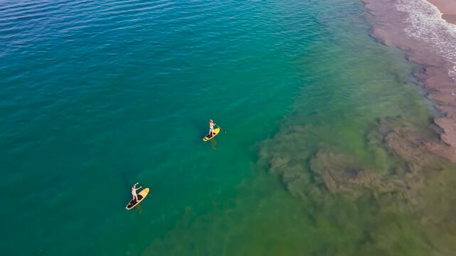 Aerial drone flying over two paddleboarders in turquoise water near Playa La Ropa beach in Zihuatanejo Mexico