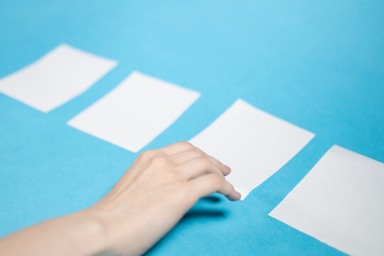 hand chooses from four blank white papers