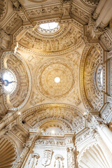 Obraz premium Seville, Spain, cathedral chapel dome with oculus, sculpted saints, heraldic shields, ribbed arches, and warm daytime light, viewed upward from the nave.