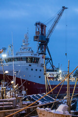 Fototapeta premium snow covered ships in Murmansk in blue winter dusk