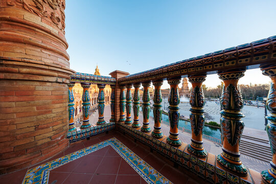 Plaza de Espana tiled balcony with azulejo balusters in Seville, Spain. Warm late afternoon light highlights brickwork, ceramics, and the semi circular arcade with towers.