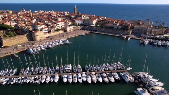 Alghero town aerial view and marina drone flight across sailing boats towards historic churches and old city walls Sardinia Italy Mediterranean coast travel destination 4k cinematic footage