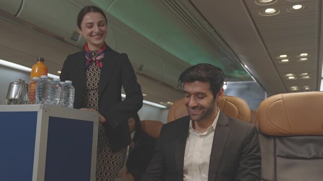 Stewardess Cabin crew or air hostess working in airplane cabin. Caucasian Female serving glass of water for passengers on board. Cart on airplane. flight attendants serve on board. business airline.
