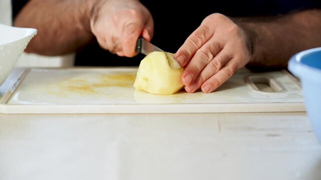 Slicing potatoes with a knife on a cutting board in a kitchen setting