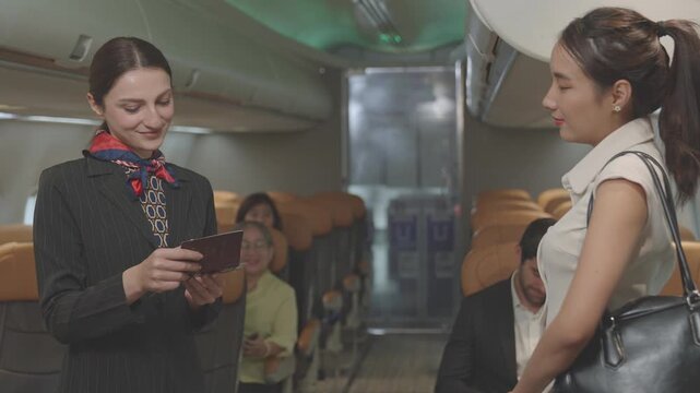 Charming flight attendants stand smiling, greeting passengers in a friendly manner, assisting with ticket checks, and assigning seat numbers. Air hostess on airplane. Business airline.