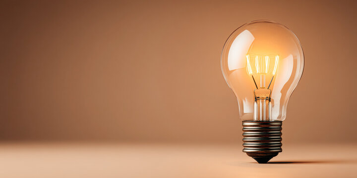 A glowing incandescent light bulb stands upright on a beige surface, symbolizing ideas and innovation with warm, soft lighting.