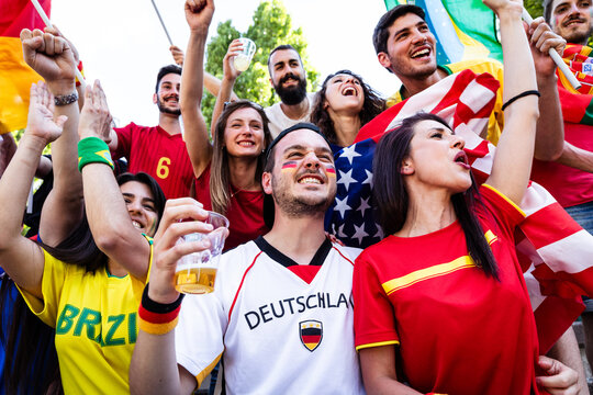 Sports fans supporting team with national flags cheering together