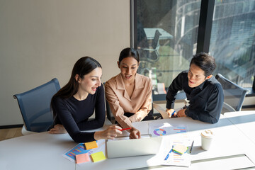 Group of diverse business team collaborating discussing on creative project using laptop. Professionals businesspeople brainstorming startup strategy during informal meeting in corporate workspace