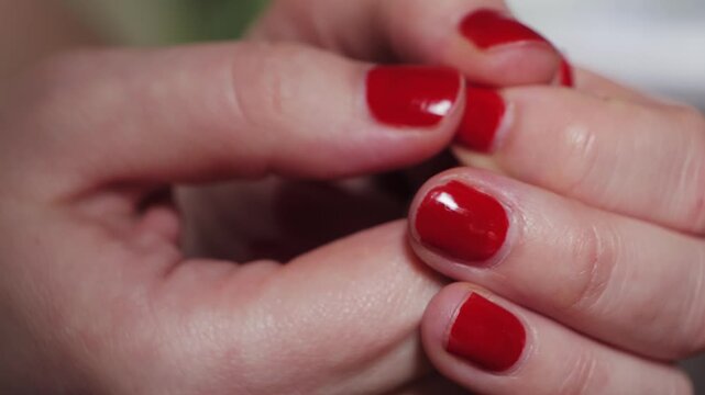 Close-up of fidgeting hands, touching nail polish, and picking at the nail polish is a common behavior often associated with stress, anxiety, and boredom.