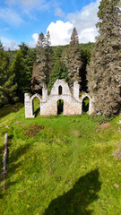 Fototapeta premium Cinematic Aerial View of the Creag Ruadh Folly, A Majestic 18th-Century Stone Ruin Hidden in the Dense Highland Forests of Evanton, Scotland - Architectural Heritage Photography.