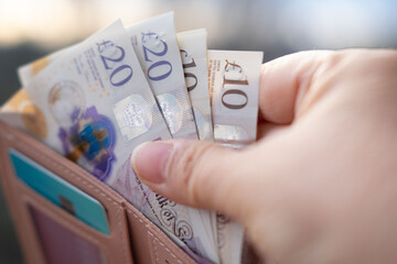 wallet with British GBP banknotes, cash in female hands, counting uk pounds bills, paper money,...
