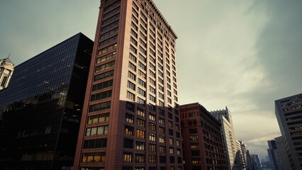 sunlit brick highrise at dusk, towering masonry facades rise above narrow street canyon, warm light casts long shadows across ornate windows and carved © icetray
