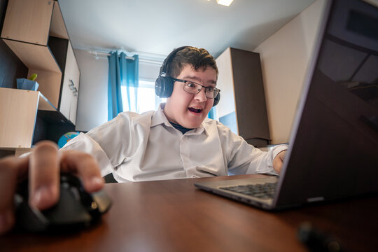 Pretty teenager playing computer game at home late. gamer boy in headphones screams while playing on a laptop