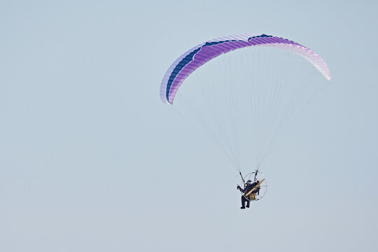 The motoparaplan and the pilot fly against the blue sky. Paralet and means of small aircraft