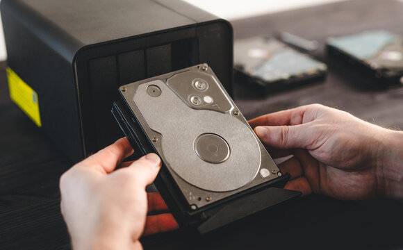 Man Holds A Hard Disk Drive From A Home Nas Server, Maintenance On The Nas Server