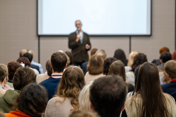 Conference audience listening to speaker during presentation in lecture hall, professional seminar atmosphere, focus, learning, engagement. © Anton Gvozdikov