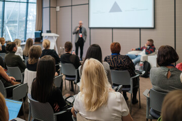 Fototapeta premium Business seminar, speaker presenting to engaged audience in conference room, networking, learning, professional atmosphere.
