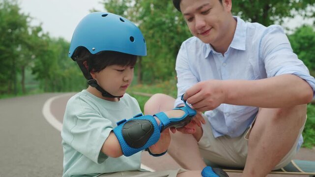 Dad assists his son with safety equipment before skateboarding