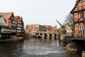 The historic Old Crane stands at the riverbank between half timbered houses and brick buildings of the old town. The calm river and bridge form a typical view of the historic northern German city. © Heidi