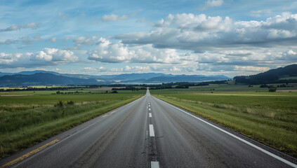 Endless asphalt road stretching towards distant mountains under a cloudy sky