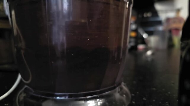 Chopper grinding dark ingredients inside food processor bowl. Appliance mixing food for meal preparation in kitchen. Domestic cooking process for healthy culinary.