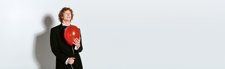 Obraz premium Elegant young man in tuxedo holds balloon in joyful celebration moment