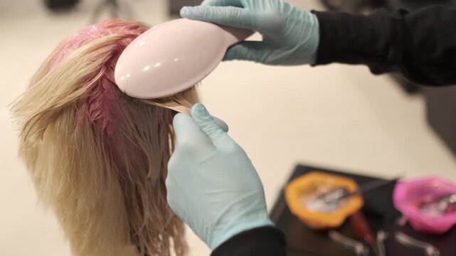 Professional stylist applying pink hair dye to a mannequin head in a hair salon setting