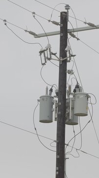 Utility power pole with transformers, insulators, cross-arm, wires. vertical video