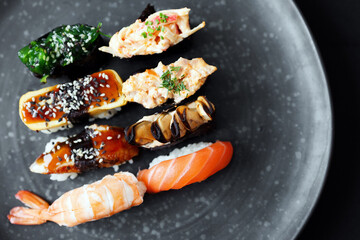 Exquisite Japanese sushi nigiri and gunkan maki served on a minimalist dark plate, showcasing fresh ingredients for a meal © muse studio