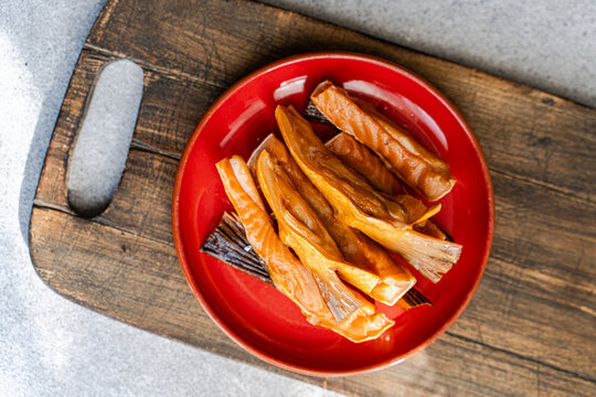 Overhead view of a plate of Smoked salmon fillets on a wooden chopping board