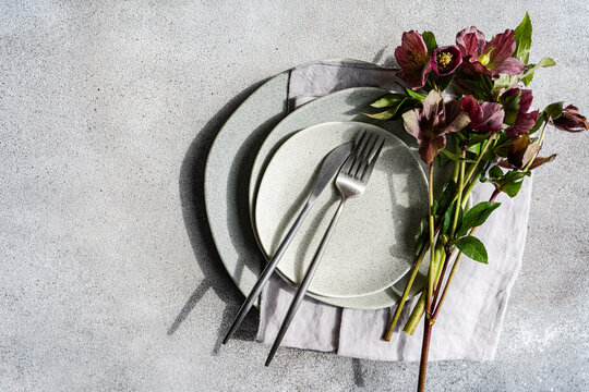 Close-up overhead view of a springtime place setting with fresh purple hellebore flowers on a table