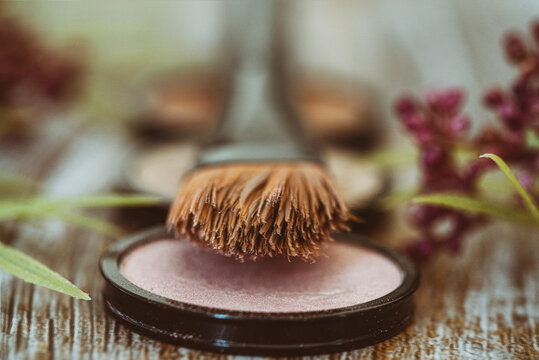 Close up of a make-up brush and three assorted make-up powder compacts