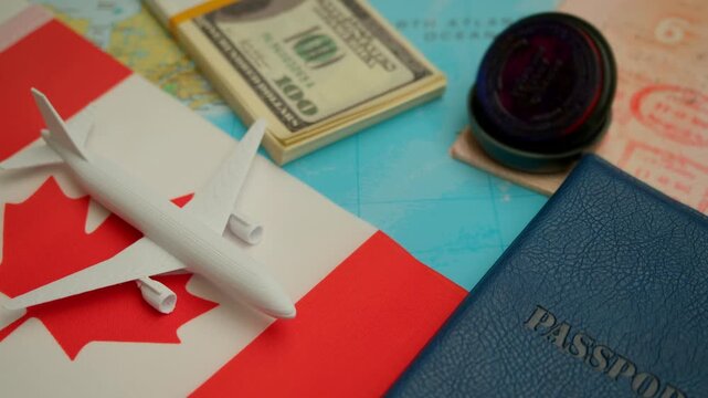 Airplane landing near passport and money stack on world map showing Canada flag, representing global tourism and visa application.