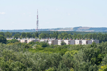Obraz premium Housing estate houses surrounded by green forest landscape with a transmission tower in the background