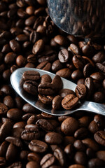 Naklejka premium close-up of roasted coffee beans with silver spoon reflecting warm earthy tones