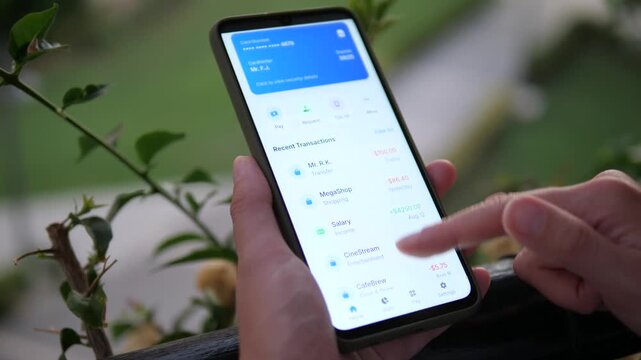 Person managing money via mobile bank app while outdoors. Scrolling through expenses and income. Concept of financial freedom, digital lifestyle, and online payments. Perfect for marketing, business