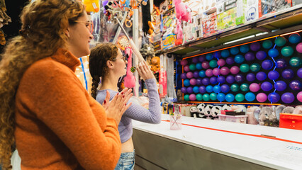 Friends enjoying carnival games and shooting balloons at a fun fair © pablo