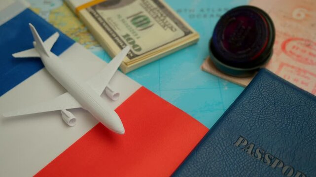 Passport with visa stamp, dollar currency, and airplane model on map background with France flag, concept of overseas trip and Schengen visa approval.
