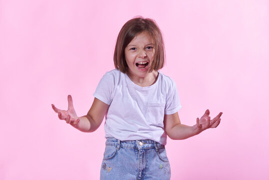 Young girl screaming loudly while making expressive hand gestures, showing intense anger and frustration during an emotional outburst on a pink studio
