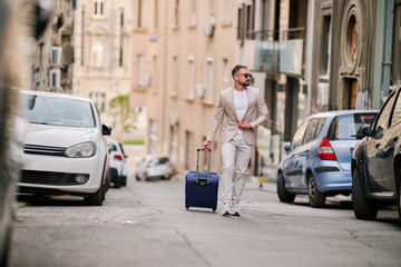 Stylish man walking with suitcase on a city street, traveling for business or vacation, exploring urban life with luggage