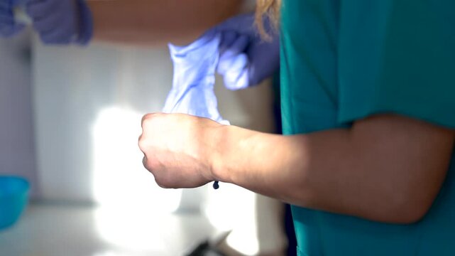 Nurse donning disposable gloves for stoma care following hygiene protocol and aseptic technique in clinical setting