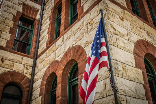 Close Up of American Flag In Front of Stone and Brick Courthouse Building in Stephenville, Texas