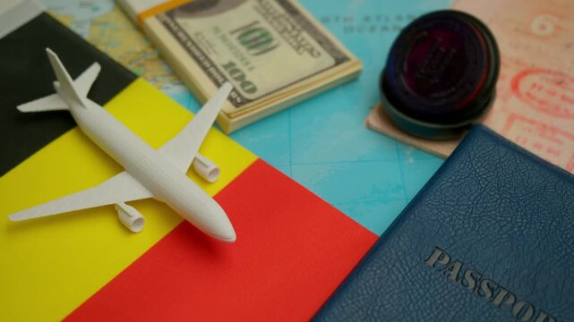 Travel concept with airplane, stamped passport, and dollar notes over world map showing Belgium flag, symbol of European tourism and culture.